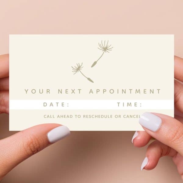 Two Hands Hold A Light Beige Appointment Reminder Card Featuring Two Simple Dandelion Illustrations. The Card Indicates Space To Write The Date And Time Of The Next Appointment.