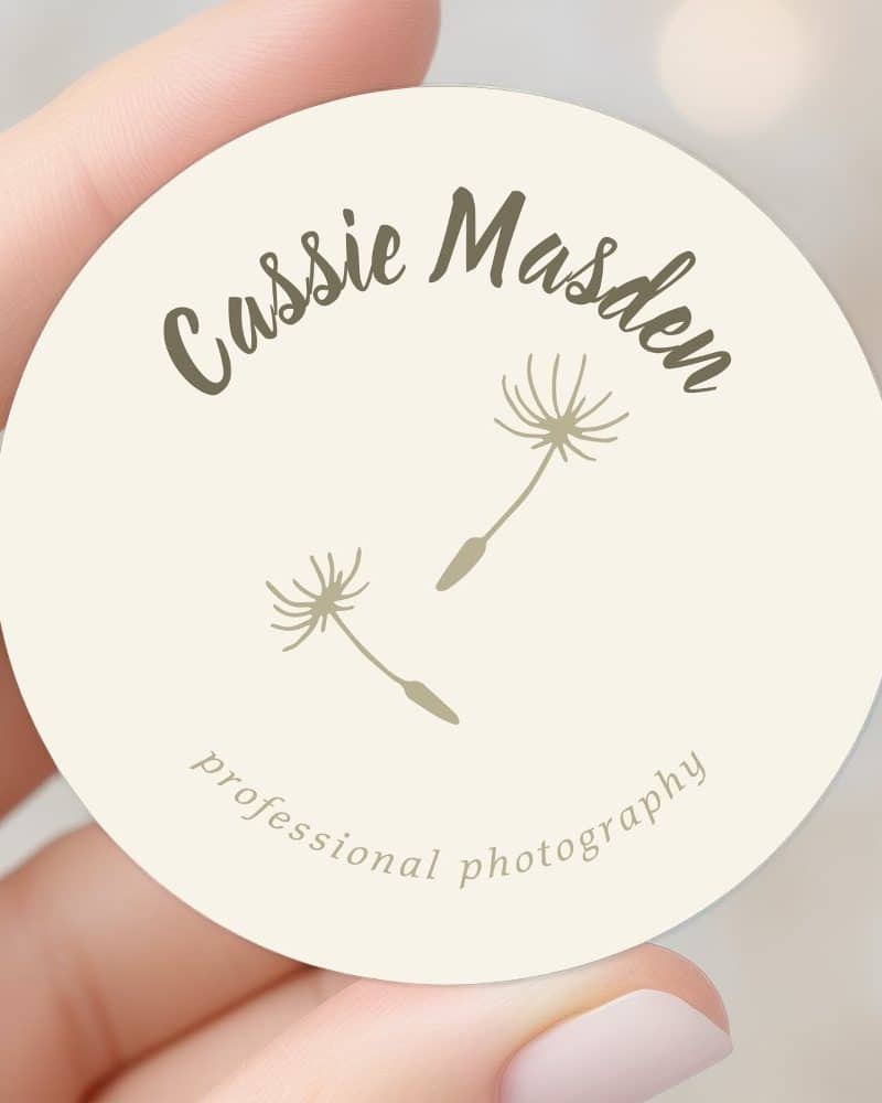 A hand holds a round business card featuring the name Cassie Madsen and two stylized dandelions. The text professional photography is also visible.