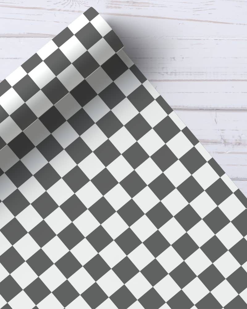 Checkered wrapping paper roll partially unrolled on a white wood surface.