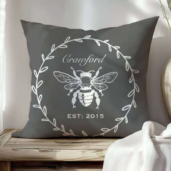 Gray Pillow With A White Bee Illustration In A Wreath, The Name Crawford And The Year 2015.