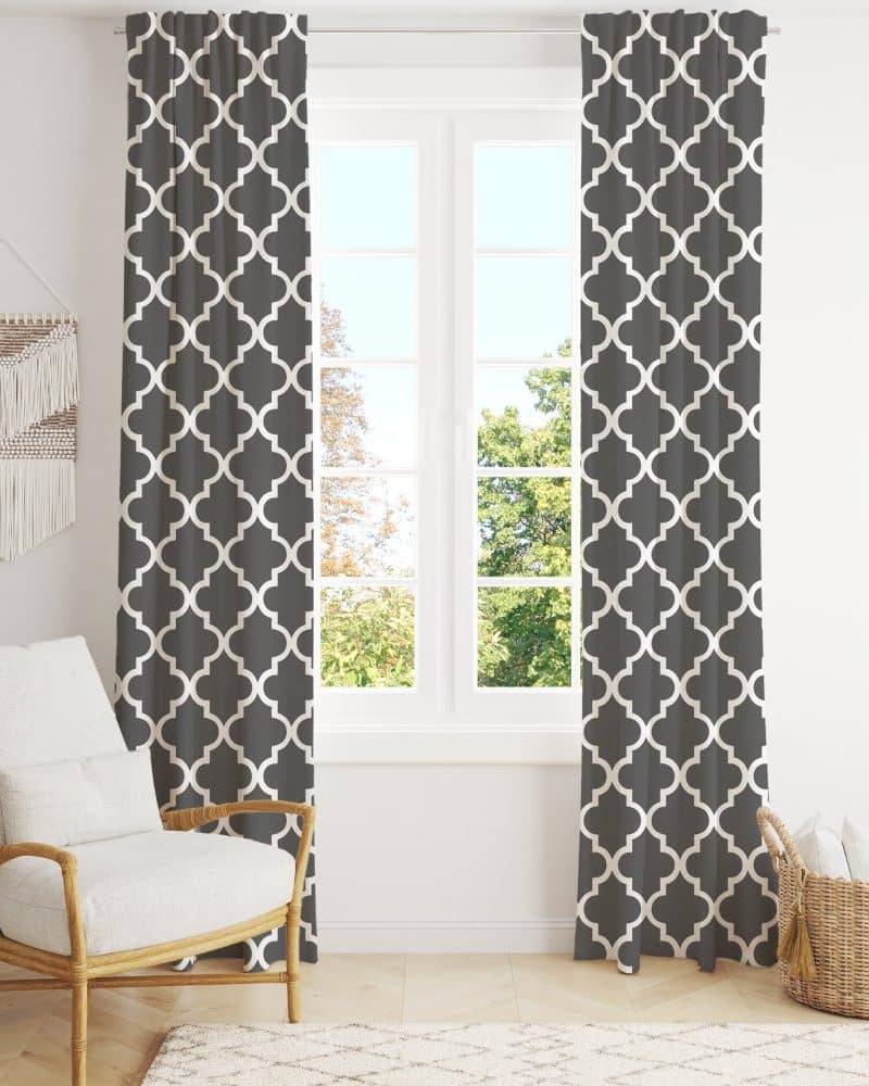 Dark gray curtains with a white quatrefoil pattern hang on a window.