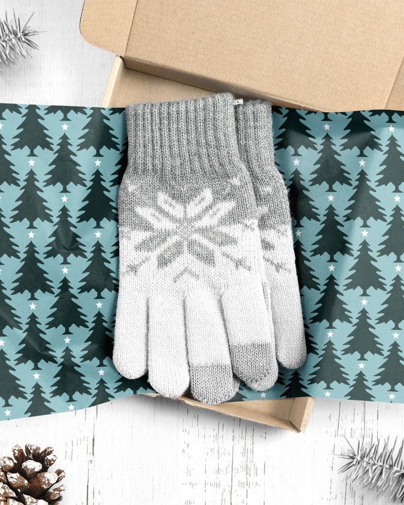 Pair of grey and white knit gloves with snowflake pattern, in a Christmas-themed gift box.