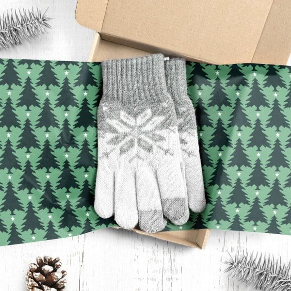 Pair Of Grey And White Knit Gloves With Snowflake Pattern, Inside A Box Lined With Christmas Tree Patterned Wrapping Paper.