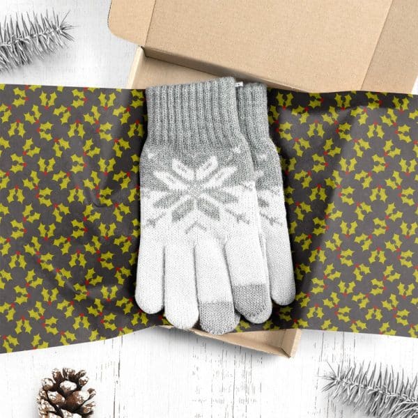 A Pair Of Grey And White Knit Gloves With A Snowflake Pattern, In A Gift Box Lined With Holly-Patterned Wrapping Paper.