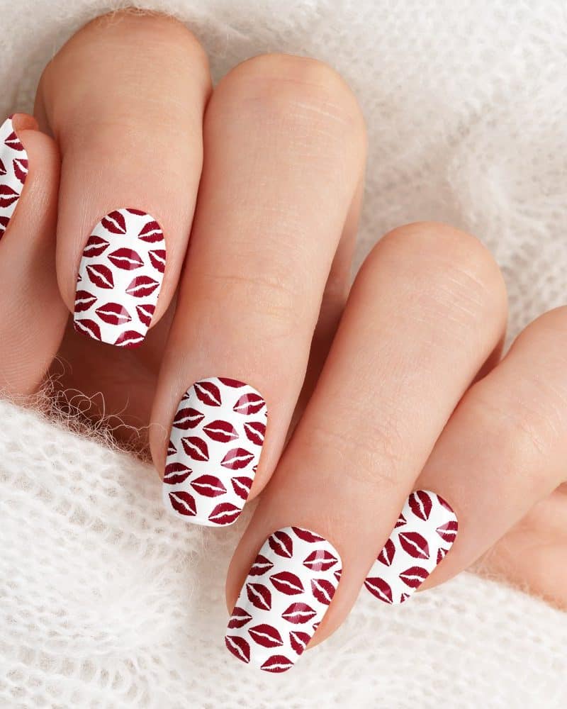 Close-up of a hand with nails adorned with a red lips print design.