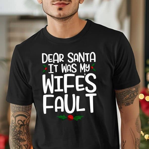 Man Wearing A Black T-Shirt With A Humorous Christmas Message: Dear Santa, It Was My Wife'S Fault.