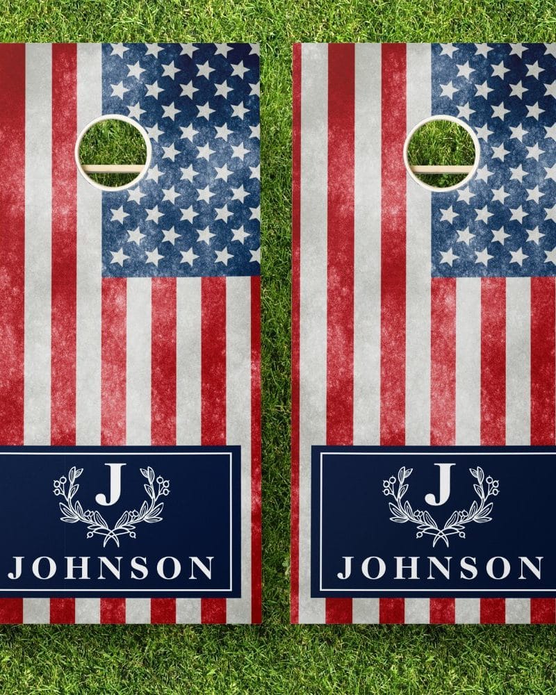 A pair of cornhole boards decorated with a distressed American flag design and personalized with the initial J and the last name Johnson.