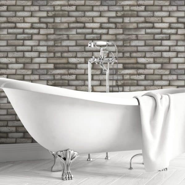White Clawfoot Bathtub In Front Of A Gray Brick Wall.