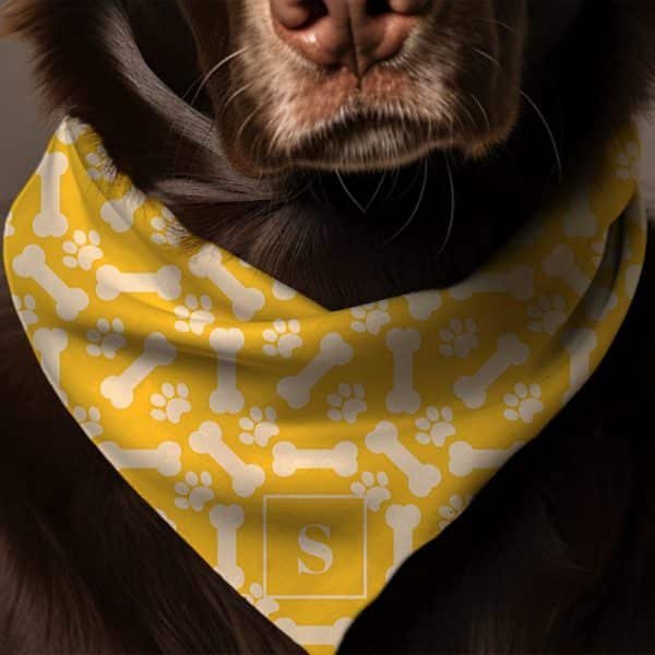 Brown Dog Wearing A Yellow Bandana With A Bone And Paw Print Pattern And A Monogram.
