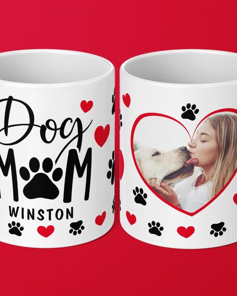 Two white coffee mugs. One mug says Dog Mom with paw prints and hearts. The other mug has a heart-shaped photo of a woman kissing a dog, surrounded by paw prints and hearts.