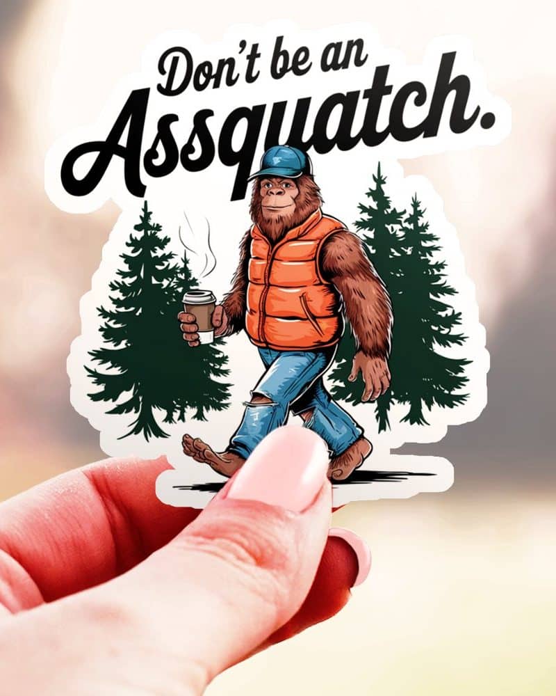 A sticker featuring a Bigfoot-like creature wearing a vest and holding a coffee cup, walking through a forest. The text above reads Dont be an Assquatch.