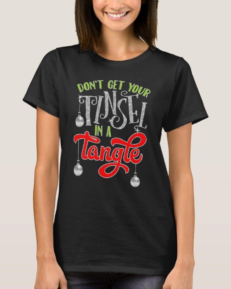 Woman wearing a black t-shirt with a Christmas design that says Dont get your tinsel in a tangle.