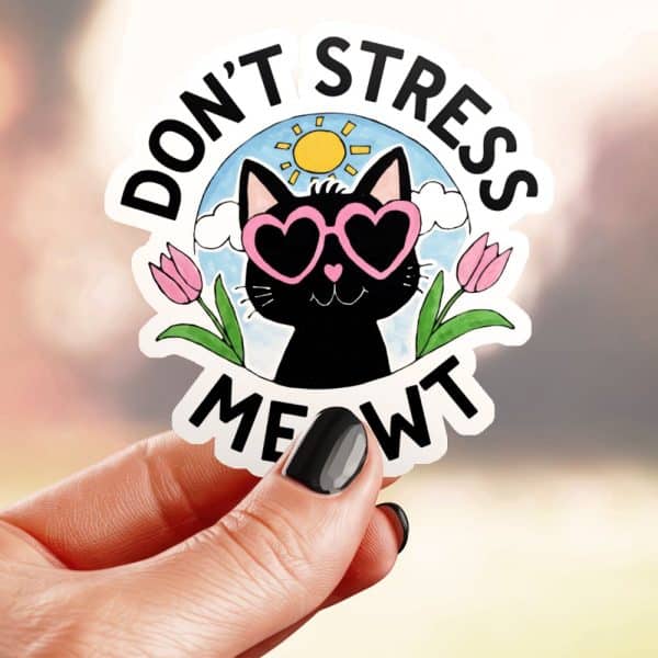 A Hand Holds A Sticker Featuring A Black Cat Wearing Heart-Shaped Sunglasses, Surrounded By Flowers And A Sun, With The Text Dont Stress Meowt.