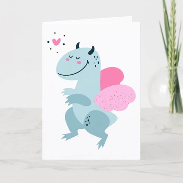 Greeting Card Featuring A Light Blue, Smiling Dragon With Pink Wings.