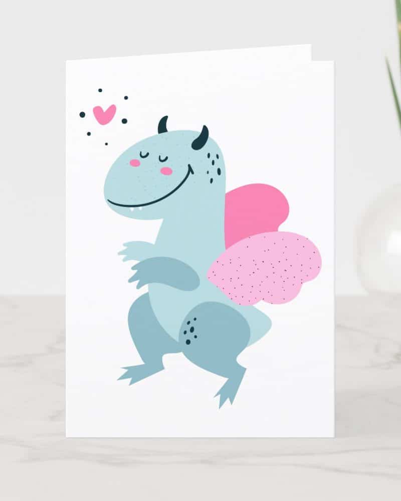 Greeting card featuring a light blue, smiling dragon with pink wings.