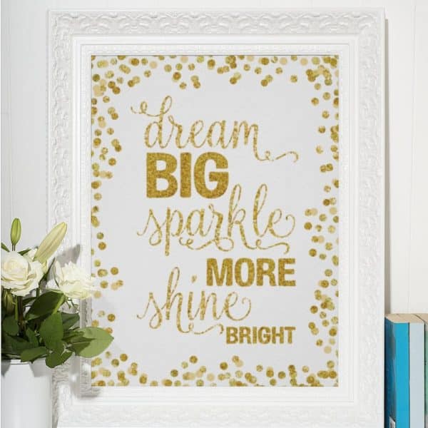 White Frame With Gold Glitter Lettering On A White Background; The Text Reads Dream Big Sparkle More Shine Bright.