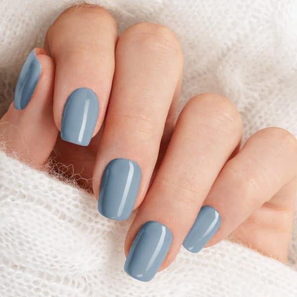 Close-Up Of A Hand With Short Nails Painted A Pale Blue-Gray.