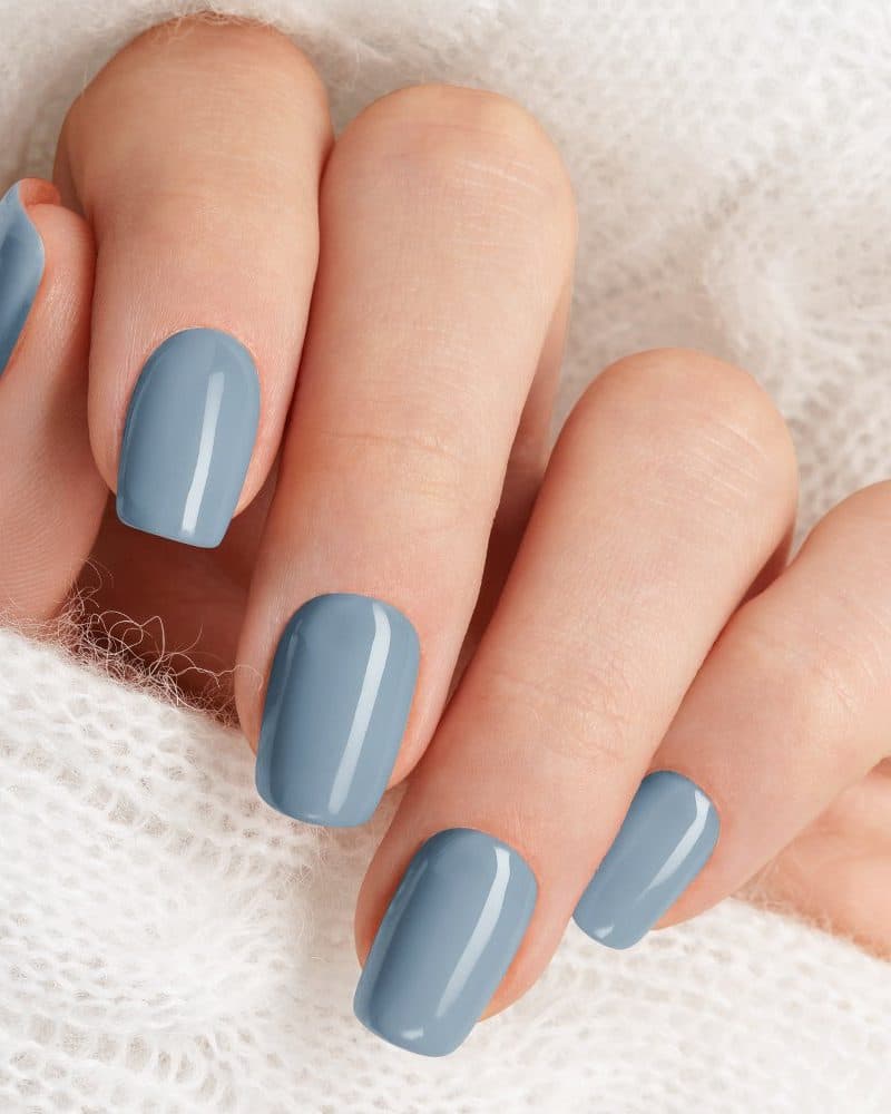 Close-up of a hand with short nails painted a pale blue-gray.