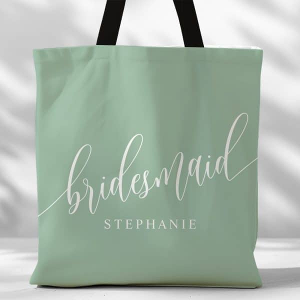 Sage Green Tote Bag With The Word Bridesmaid In Elegant Script And The Name Stephanie Printed Below.