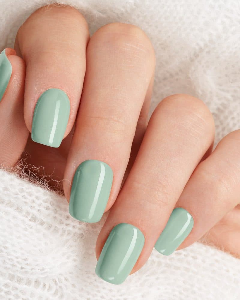 Close-up of a hand with pale green nail polish.