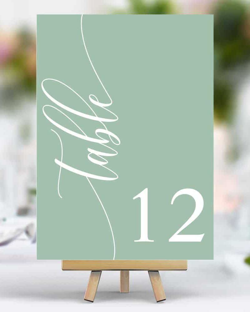 Sage green table number twelve on a small easel.