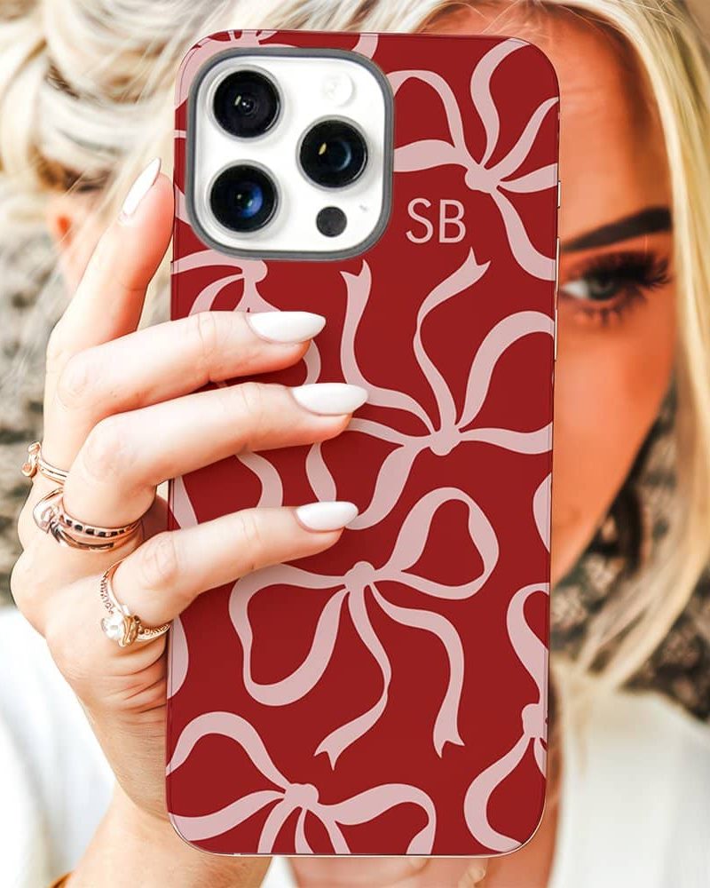 Woman holding a red phone case with a pink bow pattern.