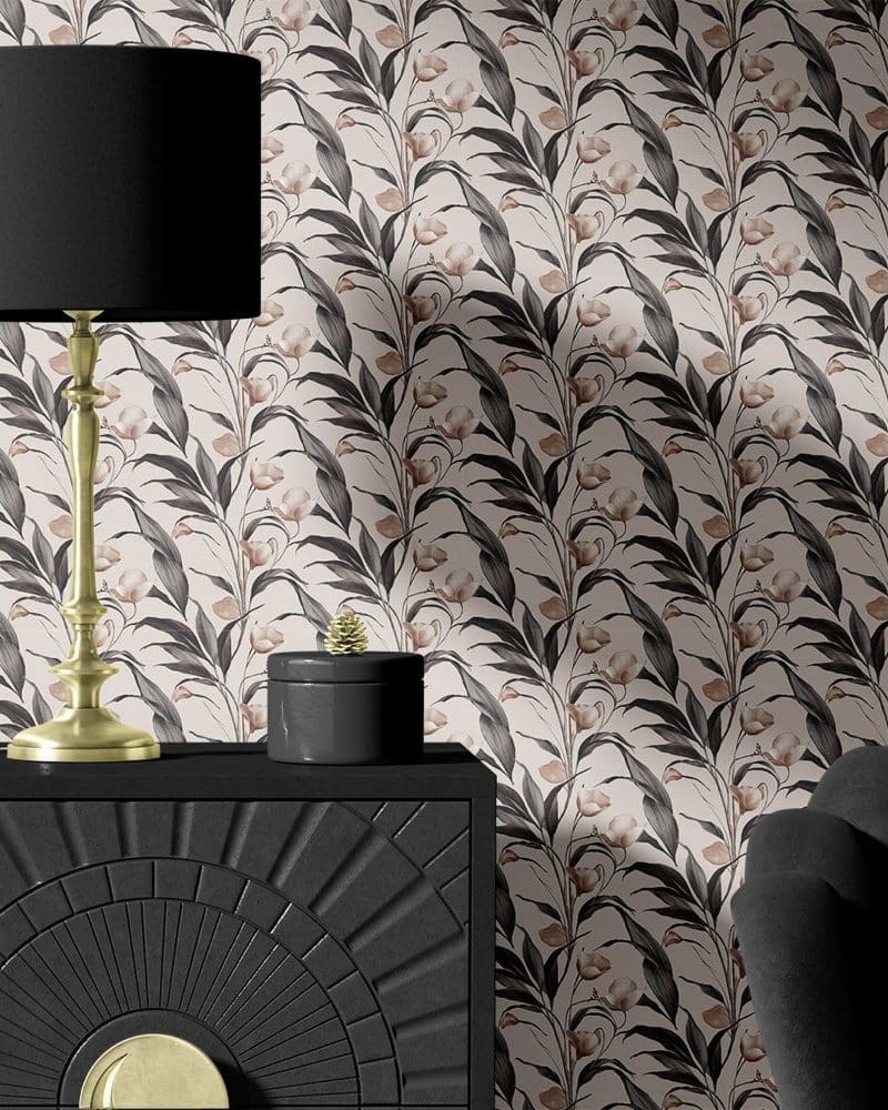 Black and gold lamp and decorative box on a black dresser against a floral wallpaper.