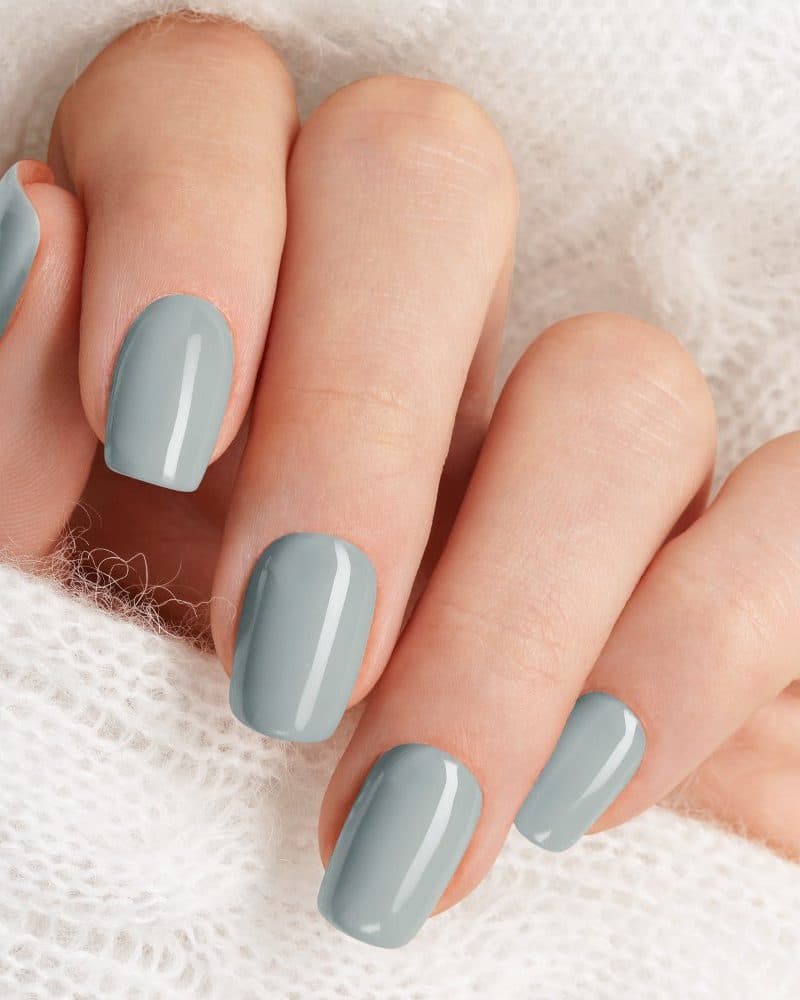Close-up of a hand with light grey nail polish.