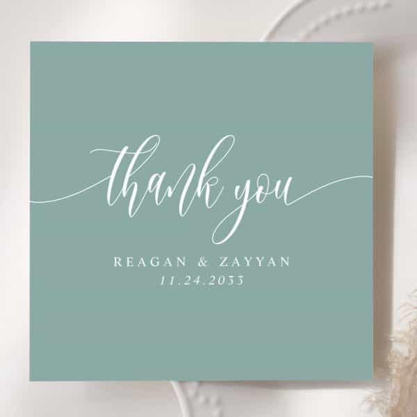 A Light Teal Thank You Card With White Script Lettering. The Names Reagan &Amp; Zayyan And The Date 11.24.2033 Are Also In White.