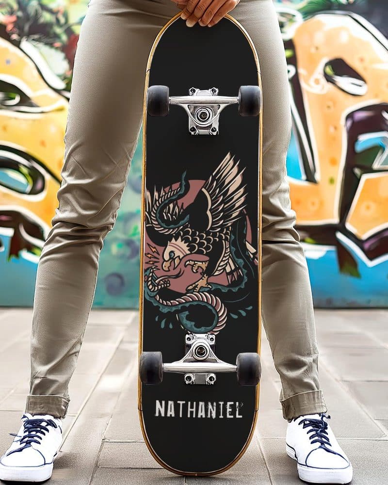Person holding a skateboard with an eagle and snake graphic and the name Nathaniel.