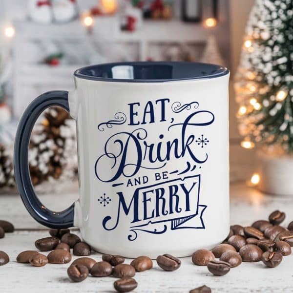 A White Coffee Mug With A Navy Blue Rim And Handle, Displaying The Text Eat, Drink And Be Merry In A Stylized Script Font.