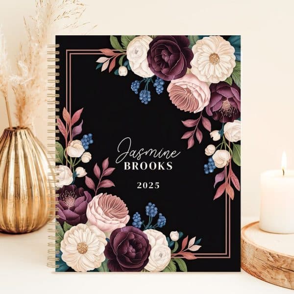 2025 Spiral-Bound Planner With A Black Cover Featuring A Floral Design In Shades Of Burgundy, Blush, And White. The Name Jasmine Brooks Is Printed On The Cover.