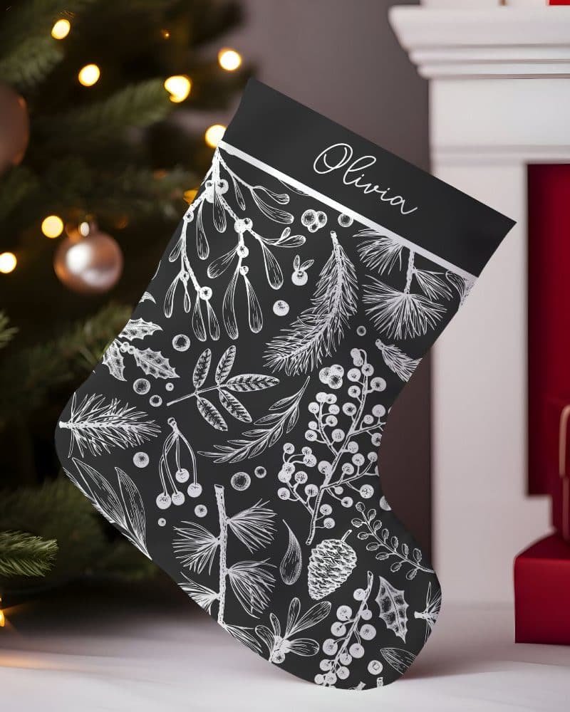 Black Christmas stocking with a silver Olivia nameplate and a white winter botanical print.