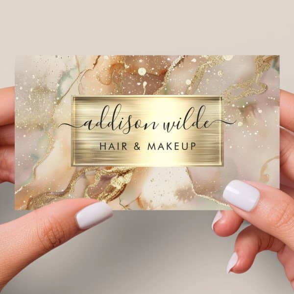 A Business Card For Addison Wilde Hair &Amp; Makeup, Featuring A Gold And Beige Marble Design.