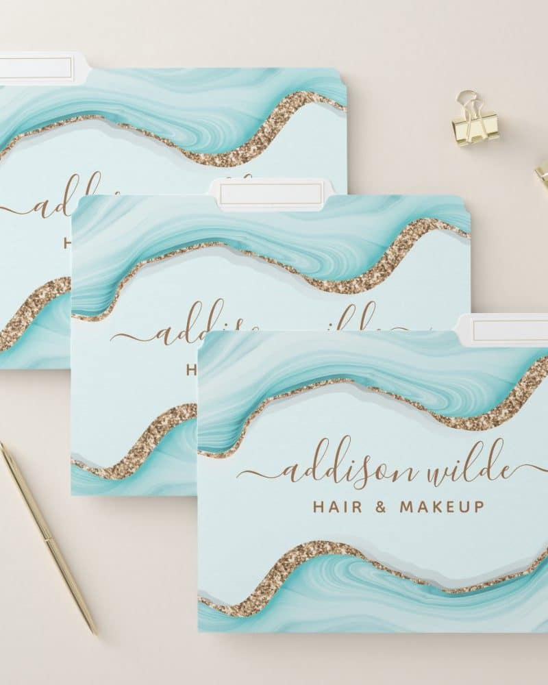 Three light teal and gold file folders with the name Addison Wilde Hair & Makeup.