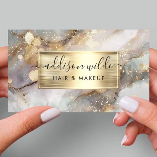 A Business Card For Addison Wilde Hair &Amp; Makeup, Featuring A Gray And Gold Abstract Marble Design.