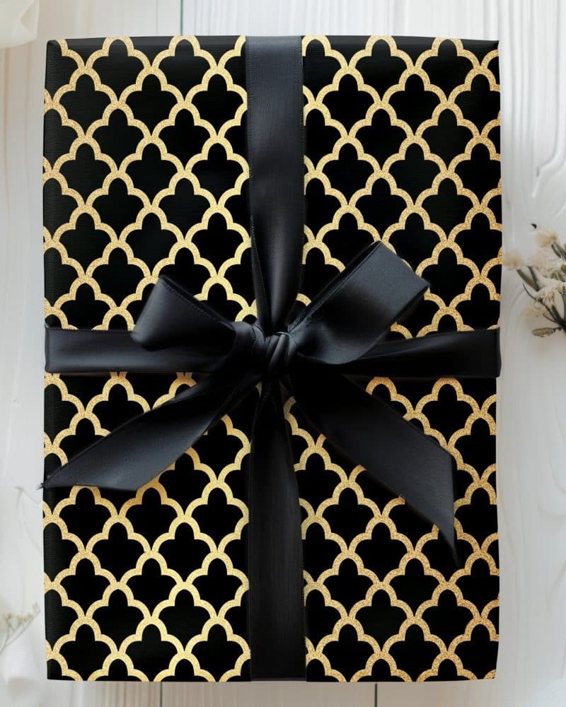 Black gift box with gold geometric pattern and black ribbon.