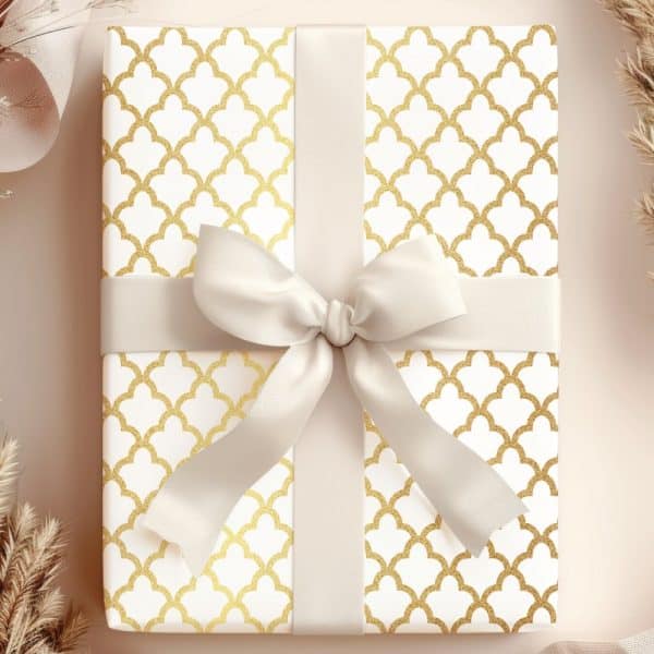 A Gift Box With A White Background And Gold Geometric Pattern, Topped With A Cream-Colored Ribbon Bow.