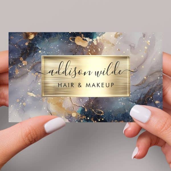 Business Card For Addison Wilde Hair &Amp; Makeup, Featuring A Dark Blue, Gold, And Grey Marble Design.