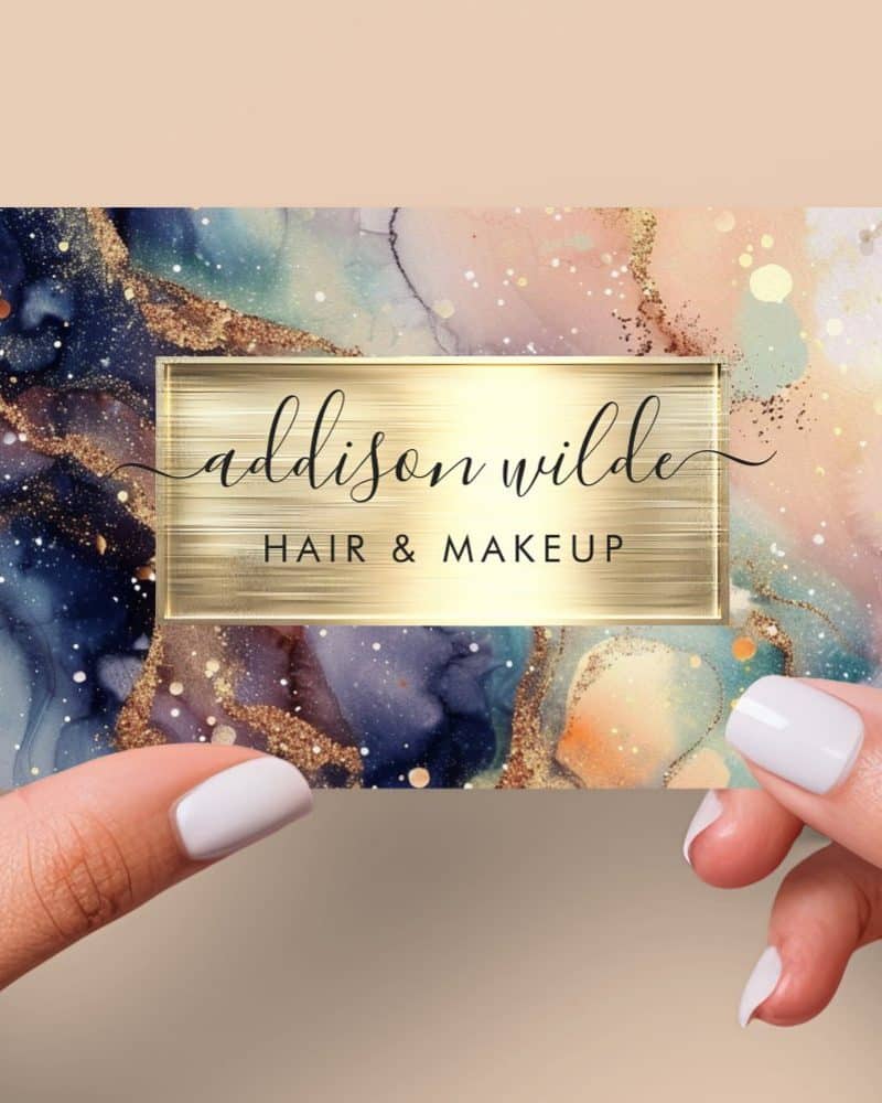 Business card for Addison Wilde Hair & Makeup, featuring an abstract watercolor design in blues, pinks, and gold.