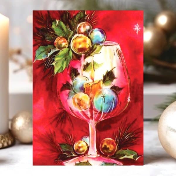 A Wine Glass Filled With Colorful Christmas Ornaments And Greenery Sits Against A Red Background.