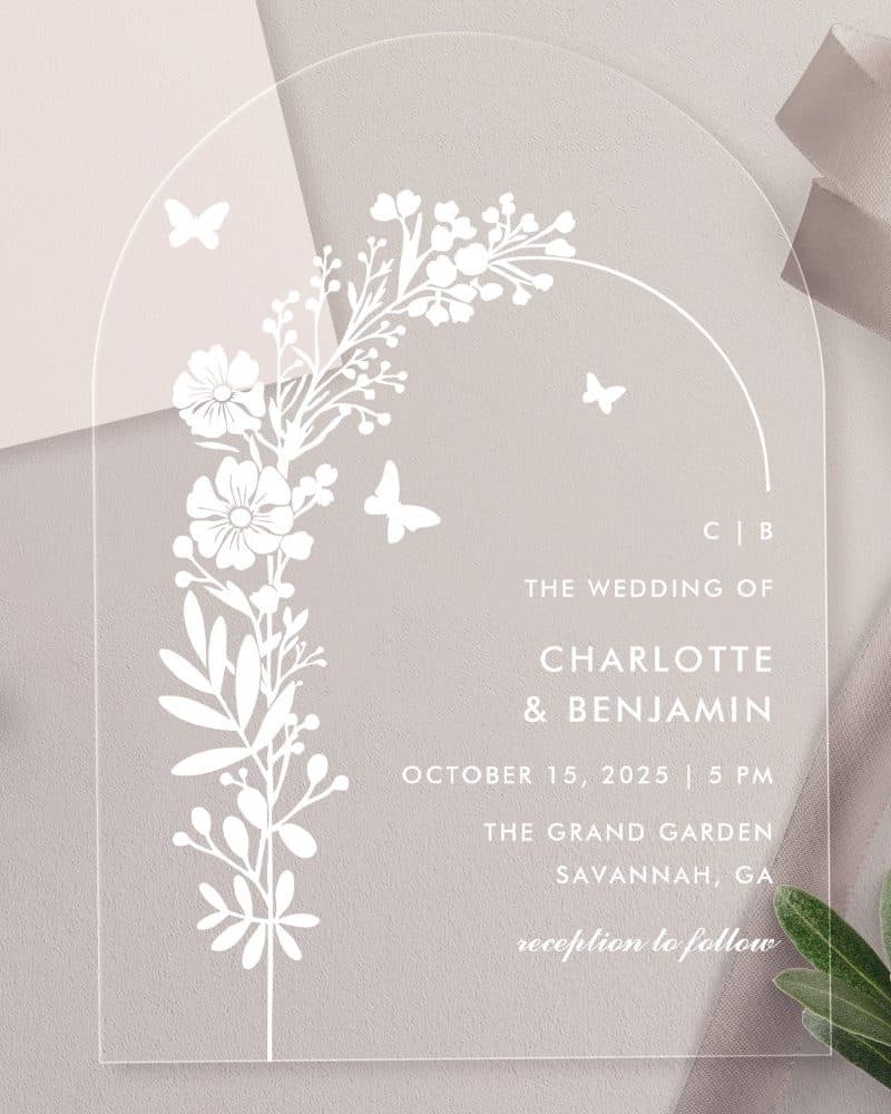 Clear acrylic wedding invitation with floral design and butterflies. Charlotte and Benjamin's wedding details are printed on the card.
