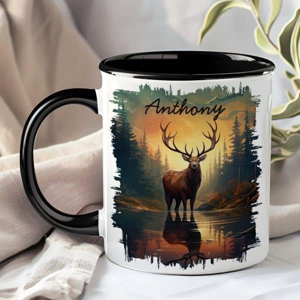 A Black And White Mug With A Black Handle, Featuring A Large Stag Standing In A Forest Reflecting In Water At Sunset. The Name Anthony Is Printed On The Mug.