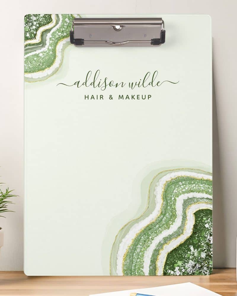 A light green clipboard with a green and white agate design and Addison Wilde Hair & Makeup written on it.