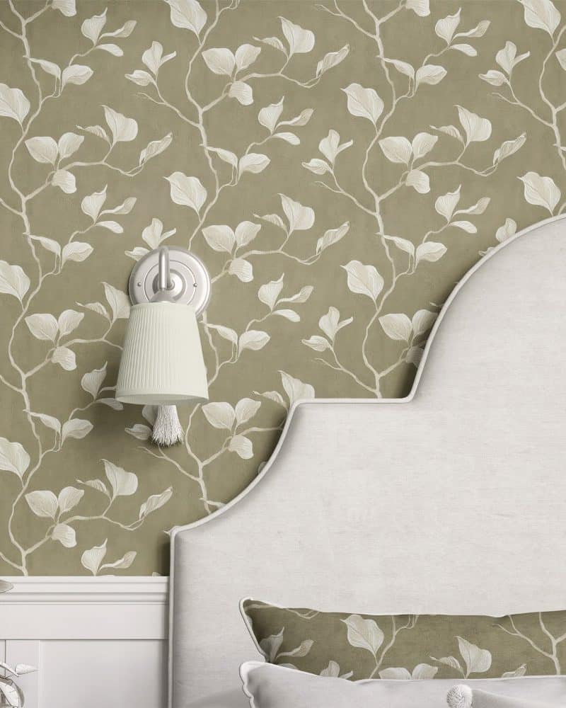 A curved headboard against a wall with a leafy botanical wallpaper.
