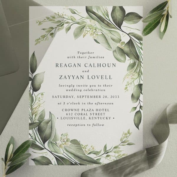 Wedding Invitation With Green Foliage Border; Reagan Calhoun And Zayyan Lovell'S Names Are Prominently Displayed.