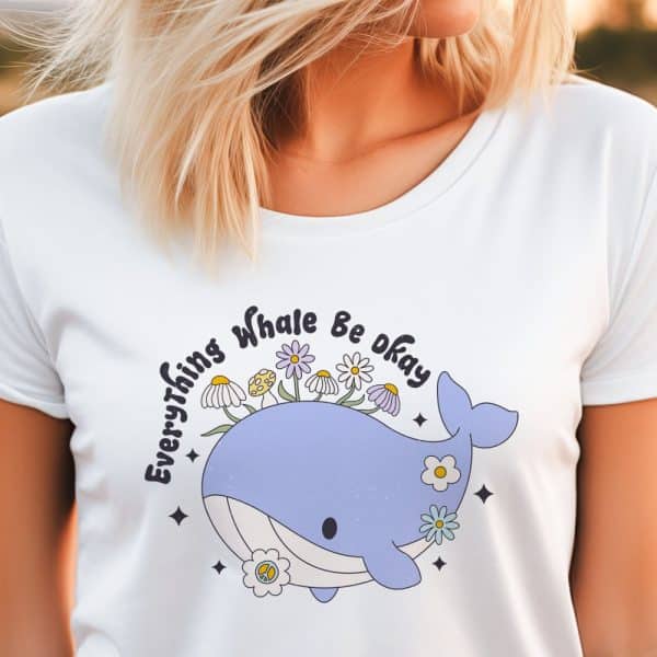 White T-Shirt Featuring A Cartoon Whale With Flowers On Its Back And The Text Everything Whale Be Okay.