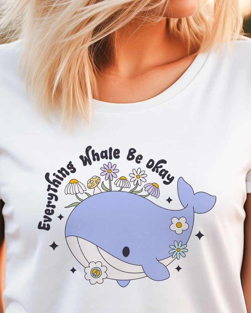 White t-shirt featuring a cartoon whale with flowers on its back and the text Everything Whale Be Okay.