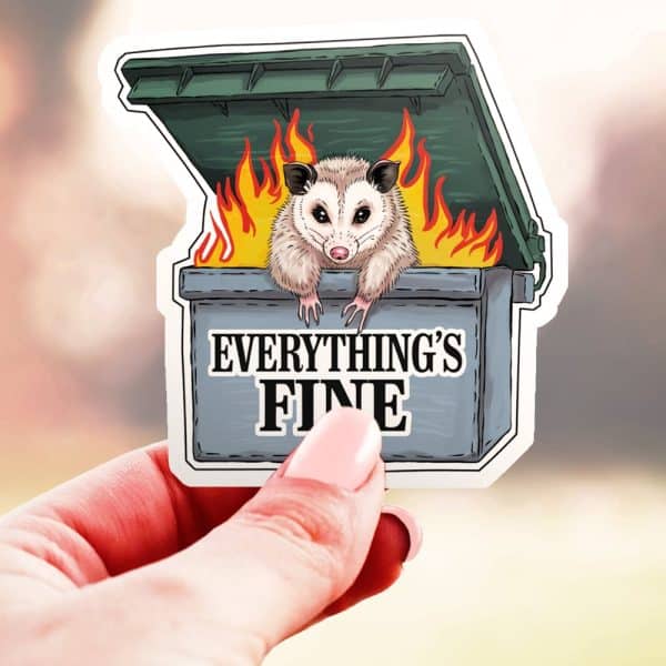 A Sticker Of An Opossum Sitting In A Burning Dumpster. The Text Everything'S Fine Is Below The Opossum.