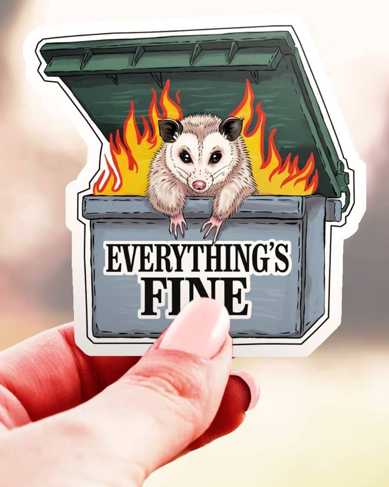 A sticker of an opossum sitting in a burning dumpster. The text Everything's Fine is below the opossum.